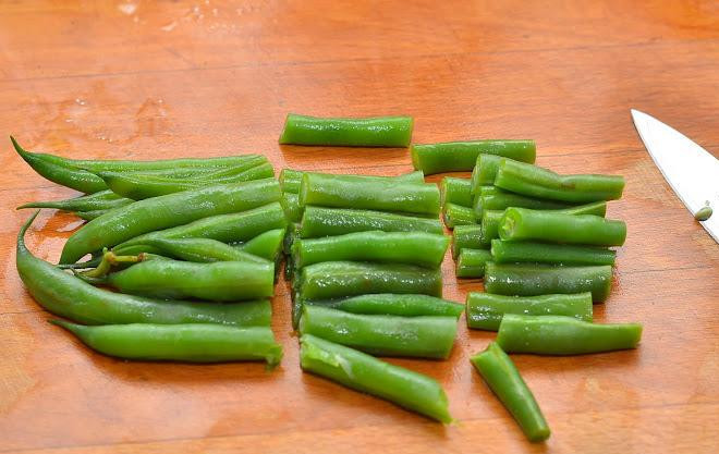 1. Этап. Салат с фисташками: Стручковую фасоль достаем из кипящей воды и сразу же обдаем ледяной - для сохранения красивого зеленого цвета. Хвостики отрезаем, оставшуюся часть нарезаем натрое.