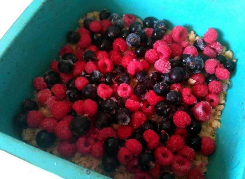 1. Этап. Лимонный крамбл с ягодами: Распределите половину получившейся лимонной крошки по дну формы для выпекания. Сверху выложите ягоды.