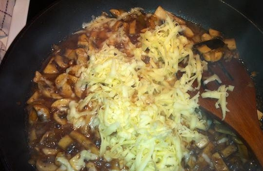 1. Этап. Говядина в сливочно-грибном соусе: Натрите сыр на крупной тёрке, внесите его на сковороду. Как только он расплавится, добавьте сливки. Тушите 3 минуты на медленном огне. Затем добавьте специи, перемешайте и отключите огонь.