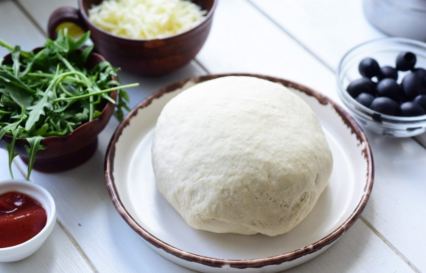 1. Этап. Пицца на сухом молоке: Замесите мягкое тесто, не прилипающее к рукам. Округлите тесто в миске, оставьте в покое на 40 минут, накрыв кухонным полотенцем.