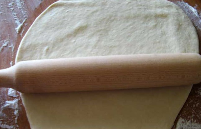 1. Этап. Вареники на кефире: Когда тесто будет готово, отрываем от него небольшой кусочек и раскатываем его в тонкий пласт.