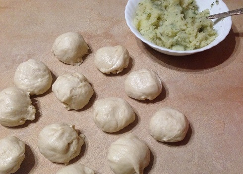 1. Этап. Дрожжевые пирожки с картофельной начинкой: Смазываем стол растительным маслом и делим тесто на 12 кусочков.