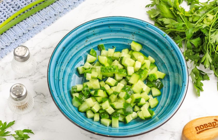 1. Этап. Салат с масляной рыбой: Нарежьте огурец пластинами, а их — мелкими кубиками. Высыпьте нарезку в салатник или глубокую миску.