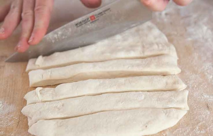 1. Этап. Чесночные узелки: 1. Раскатайте тесто в толстый пласт, затем нарежьте его небольшими полосками.