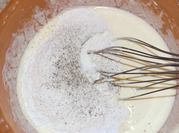 1. Этап. Рецепт кляра для мяса: К получившейся смеси добавьте часть муки с содой и перемешайте. После того как масса стала без комочков, отправьте вторую часть муки, соль и перец.