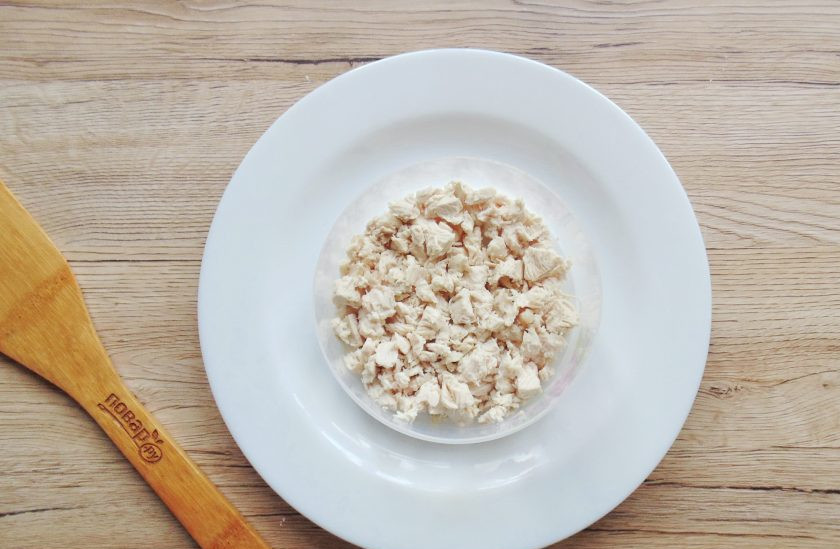 1. Этап. Салат Луиза: Отварную куриную грудку нарежьте мелким кубиком и выложите на тарелку используя кулинарное кольцо. Если грудку при варке не солили, немного посолите и поперчите.