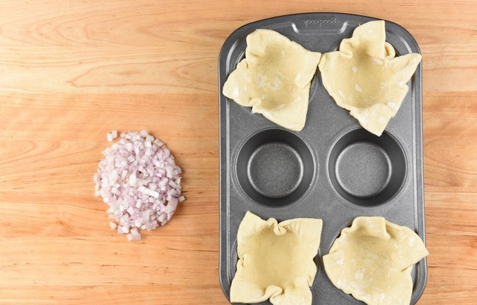 1. Этап. Мини-киш с беконом: В формочки для выпечки разложите квадраты теста так, чтобы края свисали. Лук мелко нашинкуйте.