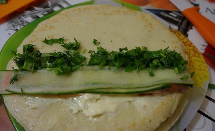 1. Этап. Блинные роллы со сливочным сыром и красной рыбой: Сверху положите огурец, а сбоку — зелень вперемешку.