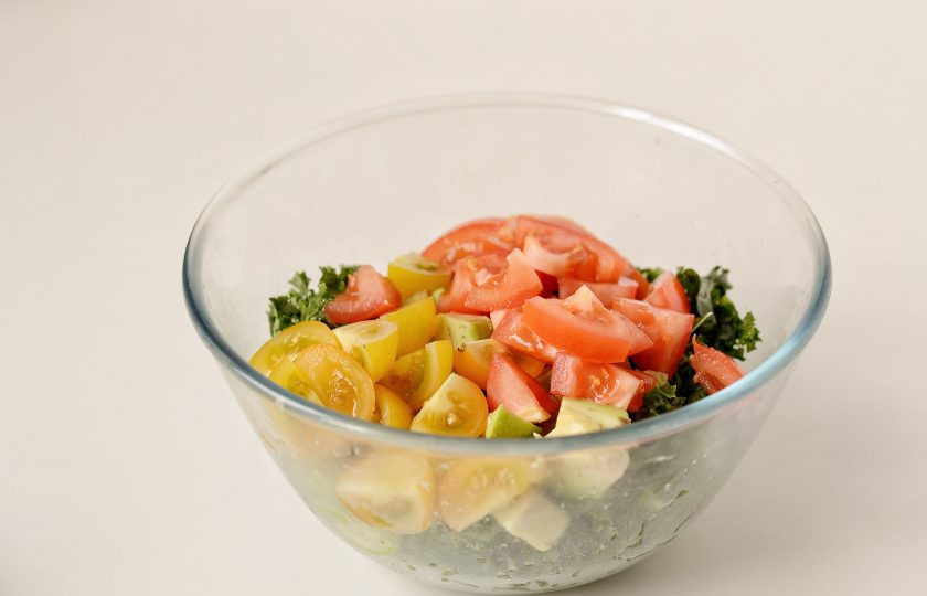 1. Этап. Салат с кейлом и авокадо: Помидоры нарежьте ломтиками среднего размера, переложите в миску. Перемешайте салат.