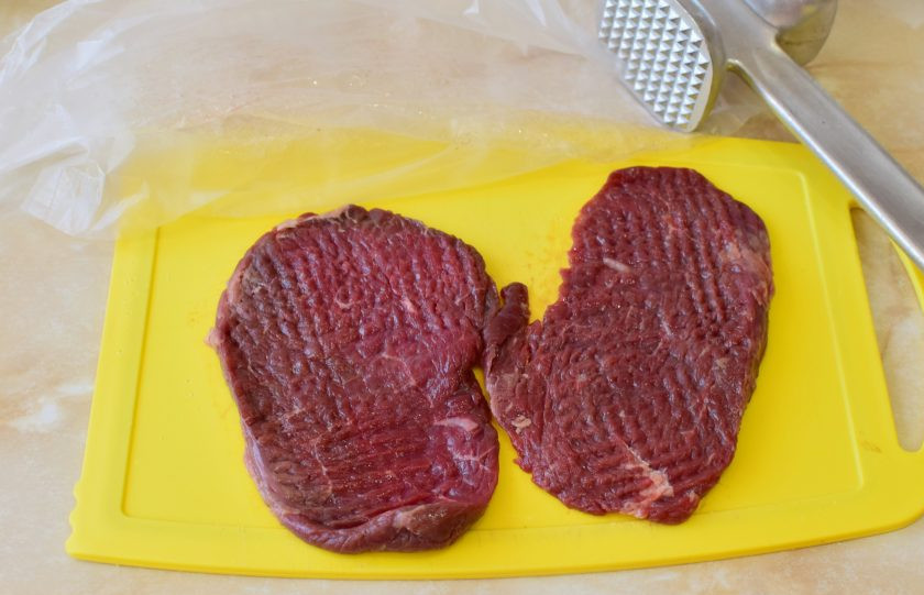 1. Этап. Телятина в духовке с ананасами: Нарежьте мясо на порционные кусочки. Немного отбейте кухонным молоточком. Это сделает мясо мягче и оно быстрее приготовится. При отбивании накройте мясо пленкой, чтобы не разлетались брызги.