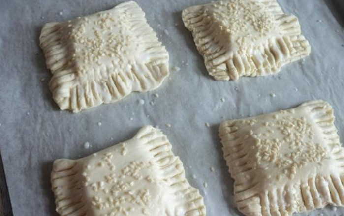 1. Этап. Слойки из готового дрожжевого теста: Выкладываем слойки на противень, застеленный бумагой для выпечки. Верхушку смазываем молоком и присыпаем кунжутом. Выпекаем в духовке 25 минут, температура — 200 градусов.