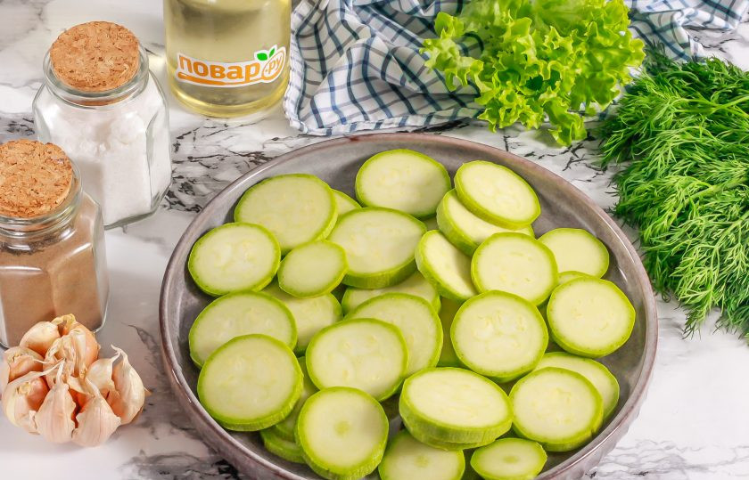 1. Этап. Кабачки запеченные с соусом и салями: Кабачки промойте в воде, срежьте с обеих сторон овощей хвостики и нарежьте кружочками. Чем тоньше будет нарезка кабачков, тем быстрее она пропечется. Посолите и оставьте на 5 минут, чтобы выделилась жидкость из нарезки.