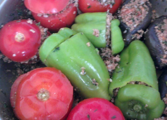 1. Этап. Долма из баклажанов по-азербайджански: Наполняем баклажаны и другие овощи начинкой. Выкладываем долму в глубокую жаропрочную емкость. Вливаем пол стакана воды, добавляем один перетертый на терке помидор. Варим 35-40 минут на среднем огне.