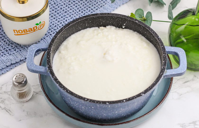 1. Этап. Адыгейский сыр на кефире: Перелейте кефир в казан или кастрюлю с антипригарным дном. Поместите емкость на плиту, включая умеренный нагрев. Сильный нагрев не включайте, так как при кипении творожное зерно разобьется на крупинки.