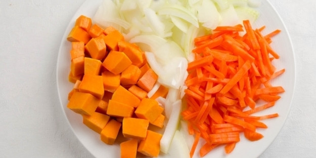 1. Этап. Плов с нутом в мультиварке: Морковь, тыкву и лук очищаем. Морковь нарезаем соломкой, лук - полукольцами, а тыкву - средними кубиками.