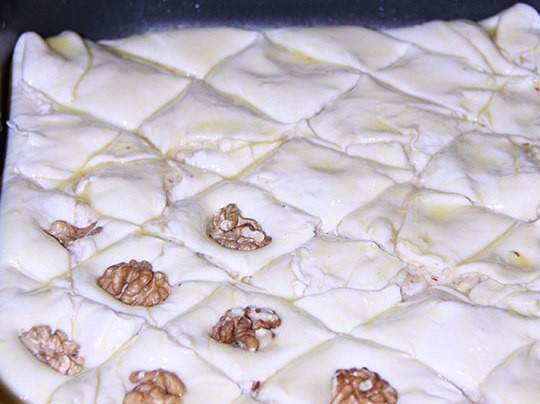 1. Этап. Пахлава из слоеного теста: Далее идет последний слой теста, накрываем им форму и заворачиваем края первого слоя. Теперь необходимо смазать верхний слой желтком и разрезать пахлаву на ромбы, сверху каждого ромба кладем грецкий орех. Отправляем форму в разогретую до 180 градусов духовку и запекаем в течение 15-20 минут.