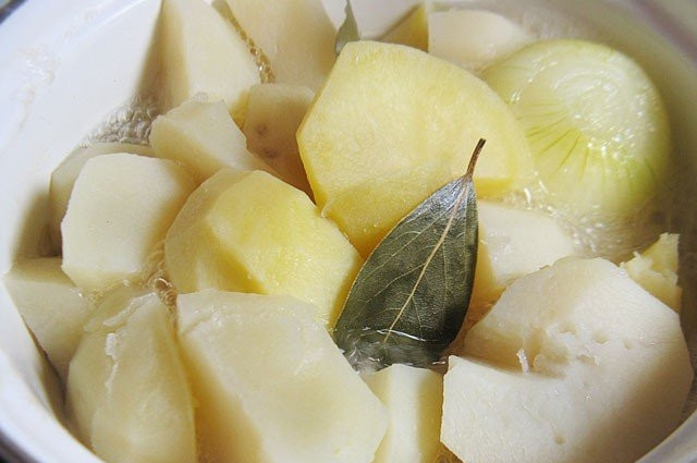 1. Этап. Пюре с молоком: Картофель промойте, очистите и крупно нарежьте. Залейте кусочки водой. Доведите её до кипения и посолите. Затем добавьте очищенную луковицу и лавровый лист. Варите картошку до готовности.