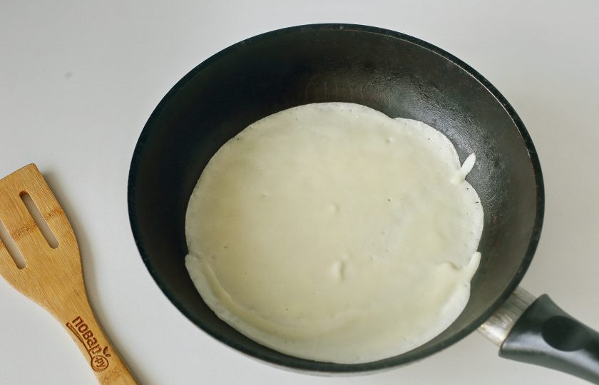 1. Этап. Блины на ацидофилине: Наливайте тесто половником на хорошо разогретую сковороду, смазанную растительным маслом, равномерно распределяя его по всей сковороде.