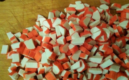 1. Этап. Салат из крабовых палочек с киви: 6. Очистите и нарежьте кубиками крабовые палочки. Время собирать салатик: первый слой — из фруктов с яйцами, потом крабовые палочки и авокадо. Повторите слои.