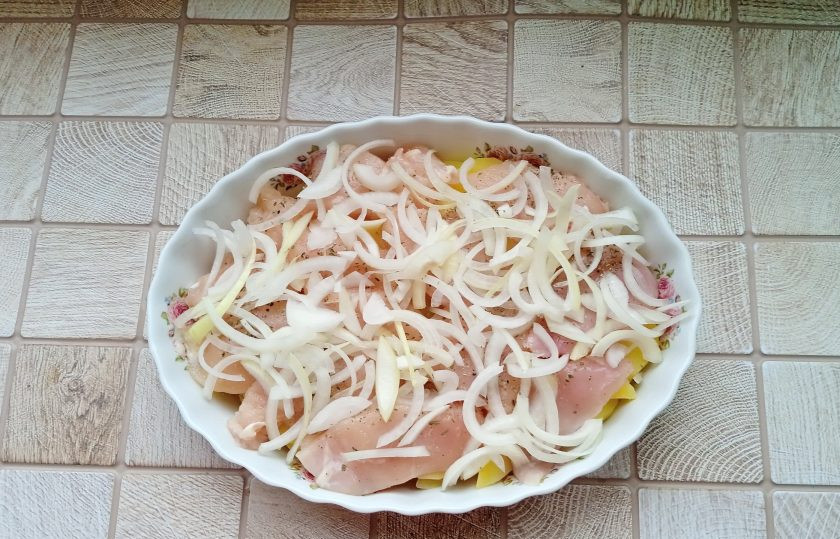 1. Этап. Курица по-французски с картошкой: Крупную луковицу очистите, помойте и нарежьте полукольцами. Выложите на куриное филе.