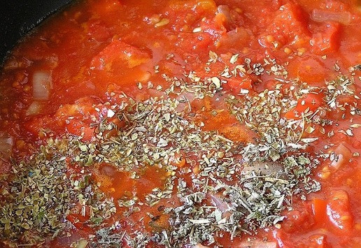 1. Этап. Закуска из яиц в красном соусе: Влейте томат, перемешайте. Добавьте орегано и шалфей. Готовьте минут пять на среднем огне, помешивая.