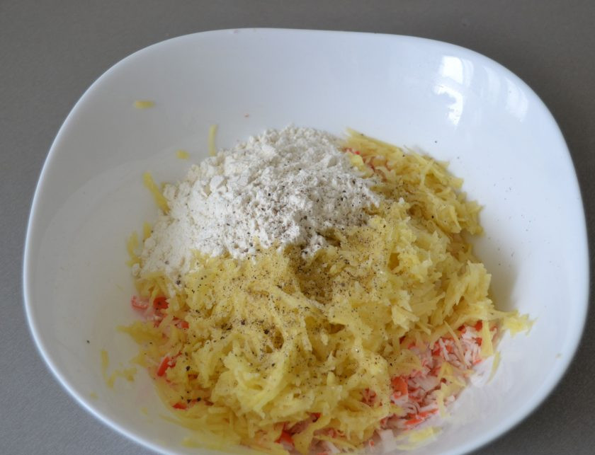 1. Этап. Драники с крабовыми палочками: Натрите на средней терке картофель, посолите, поперчите.