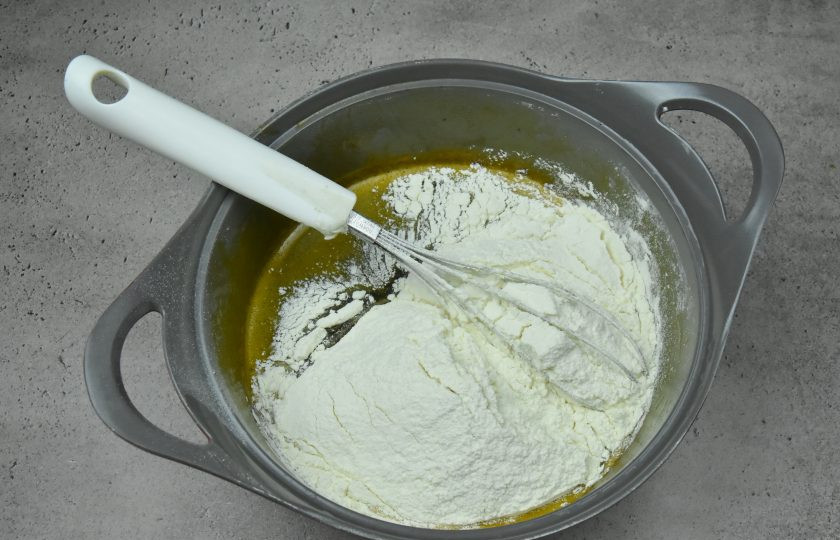 1. Этап. Торт Медок: Добавьте в сотейник к жидкой составляющей просеянную муку.