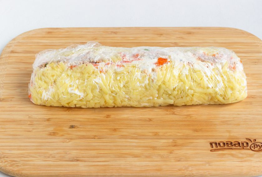 1. Этап. Салат-рулет Мимоза на Новый год 2025: Теперь аккуратно с помощью пленки подтяните салат вверх к середине с одной и с другой стороны, кончики также прикройте пищевой пленкой и уберите в холодильник на несколько часов. Затем с помощью острого ножа разделите на порции и подавайте к столу на листьях салата.