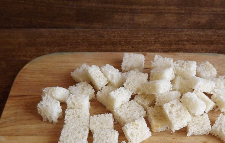 1. Этап. Салат Цезарь лучший: Ломтики белого багета очистите от корок. Затем нарежьте его на небольшие кубики. Поджарьте хлеб на сковороде или запеките в духовке, чтобы он стал золотистого цвета.