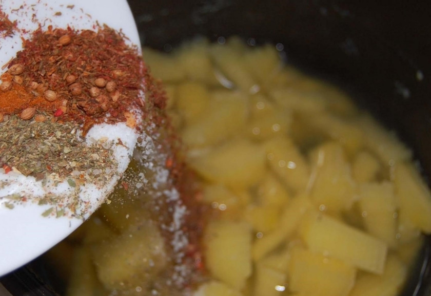 1. Этап. Тушеная картошка с тушенкой: Помойте болгарский перец. Избавьте его от плодоножки и семян. Порежьте и отправьте к готовящемуся в мультиварке картофелю. Следом отправьте специи, смешанные с сухими травами, солью, кориандром и паприкой. После того, как болгарский перец немного проварится, в чашу мультиварки отправляйте овощную поджарку.