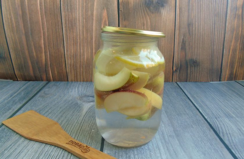 1. Этап. Компот из яблок и лимонов на зиму: Воду вскипятите и залейте крутой кипяток в банку с яблоками и лимоном. Прикройте стерилизованной крышкой и дайте постоять 20-25 минут.