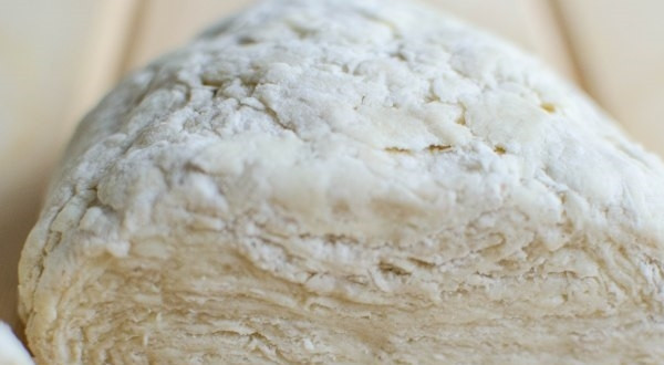 1. Этап. Тесто для торта Наполеон классическое: 4. Соедините жидкие ингредиенты с мукой и маслом, с помощью насадки для замешивания слоеного теста замесите его. Разделите тесто на 2 части и оберните в пленку, отправьте его в холодильник минимум на 30 минут.