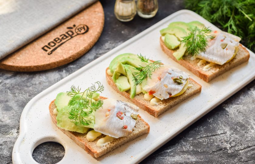 1. Этап. Бутерброды с авокадо и селедкой: Поверх лимона выложите по одному кусочку селедки.