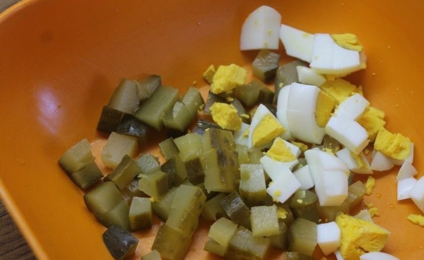 1. Этап. Салат с охотничьими колбасками: Кубиком нарежьте соленый огурец и отваренное вкрутую яйцо. Отправьте их в удобную для смешивания емкость.