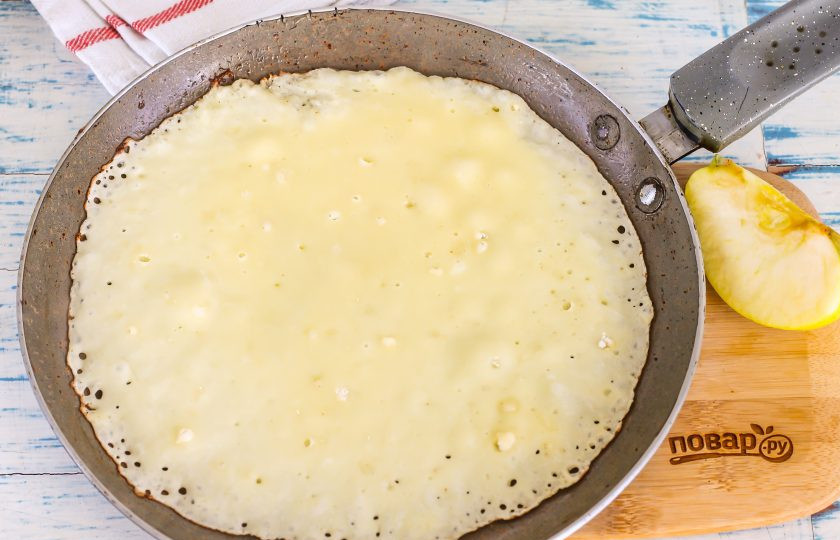 1. Этап. Блины на кефире с припеком: Прогрейте на плите блинную сковороду, смажьте ее первый раз маслом. Влейте на нее порцию теста.