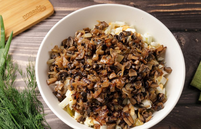 1. Этап. Салат с курицей, грибами и маринованными огурцами: Добавьте обжаренные с луком шампиньоны.