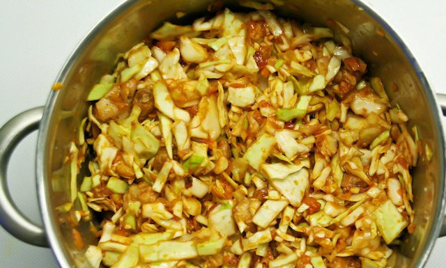 1. Этап. Cолянка тушеная: Переложите обжарку из сковороды в кастрюлю с капустой. Посолите и поперчите. Влейте немного воды, томатную пасту. Также добавьте томаты и чеснок. Всё смешайте.