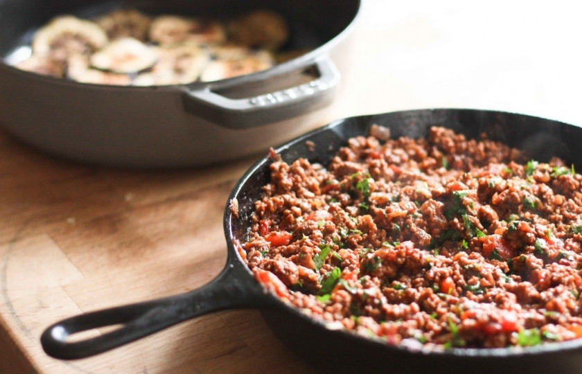 1. Этап. Мусака по-турецки: Теперь приготовим фарш. На сковороде обжарьте мелко рубленный лук на среднем огне, 3-4 минуты. Добавьте нарезанный чеснок (можете выдавить) и жарьте чеснок с луком ещё 8-10 минут. Лук станет мягким. Затем к луку и чесноку выложите бараний фарш. Тушите всё вместе 15 минут. Фарш должен стать коричневым. Вылейте лишний жир из сковороды столовой ложкой. Добавьте белое вино, нарезанные на маленькие кусочки помидоры, томатную пасту, рубленную петрушку, сахар, корицу. Посолите и поперчите. Тушите всё на среднем огне 20 минут.