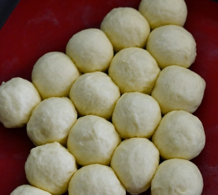 1. Этап. Булочки в виде ёлки: Затем мы еще раз обминаем тесто и делим его на 19 равных частей, формируем из каждой части небольшой шарик. Выкладываем шарики на противень, застланный пергаментной бумагой, формируя из них как бы елочку. Из 15 шариков делаем большой треугольник, а 4 оставшихся выкладываем посередине основания треугольника, оставляем шарики из теста подниматься на 30-45 минут.