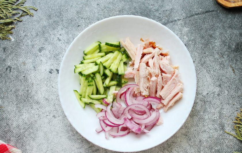 1. Этап. Салат из копченой куриной грудки с фасолью и огурцом: У копченой грудки удалите кожу и все кости, порежьте соломкой. Выложите курицу в салатник. Свежие огурцы порежьте средней соломкой, красный лук порежьте полукольцами и добавьте к курице.