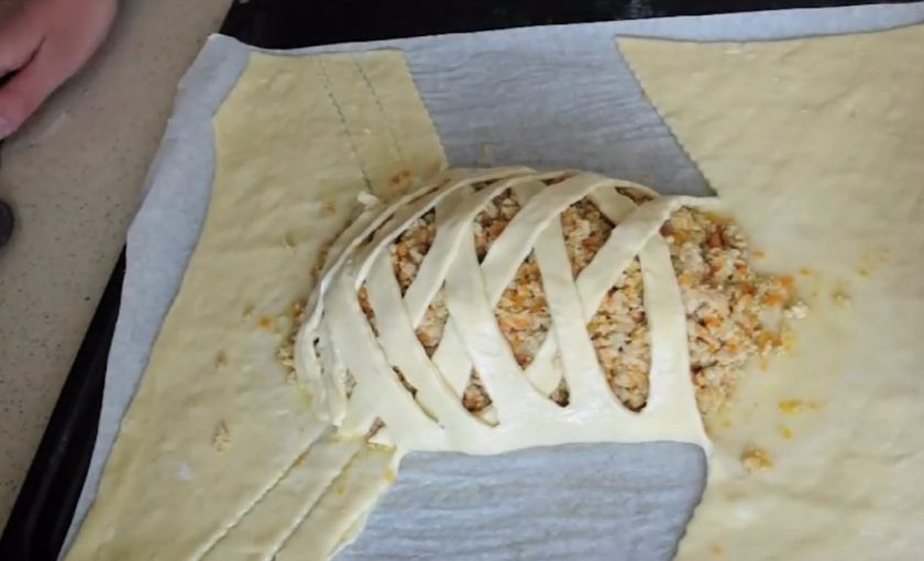 1. Этап. Пирог Крокодил: 4. Когда тесто поднимется, раскатайте его в прямоугольник с ровными краями. Переложите тесто на противень, выложите по центру начинку. По бокам разрежьте тесто на полоски, заплетите 