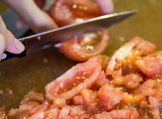 1. Этап. Кальмары с рисом: 3. Очищенные помидоры нарежьте небольшими кубиками. Часть выложите в глубокую мисочку к обжаренному луку с чесноком.