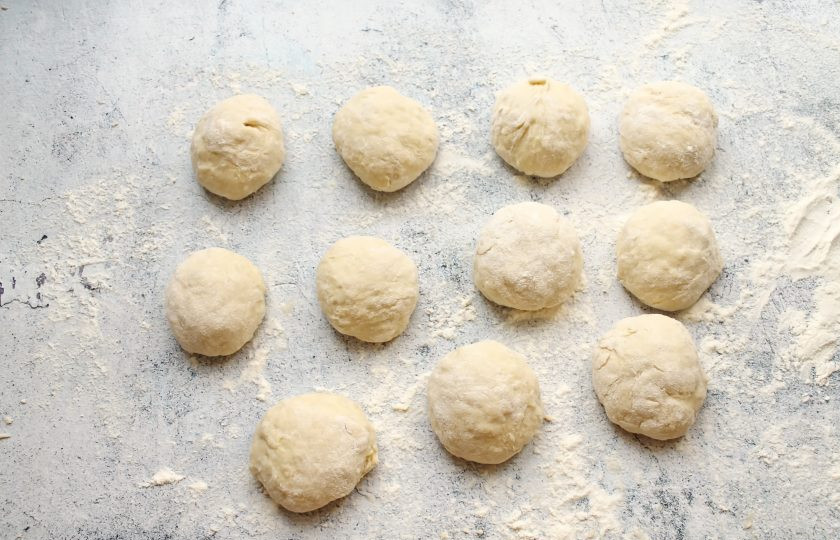 1. Этап. Пирожки на кефире и сметане: Рабочую поверхность посыпьте мукой и разделите тесто на части, сформируйте шарики.