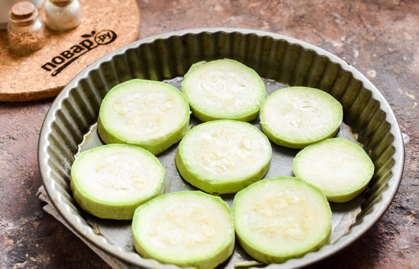 1. Этап. Кабачки под шубой в духовке: Противень хорошо смажьте растительным маслом, выложите нарезанные кружочками кабачки.