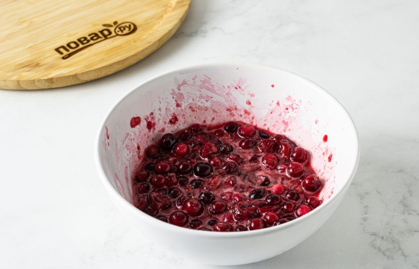 1. Этап. Галета с клюквой: Для начинки подавите половину клюквы толкушкой. Добавьте сахар и крахмал, перемешайте. Затем добавьте оставшиеся ягоды и еще раз все перемешайте.