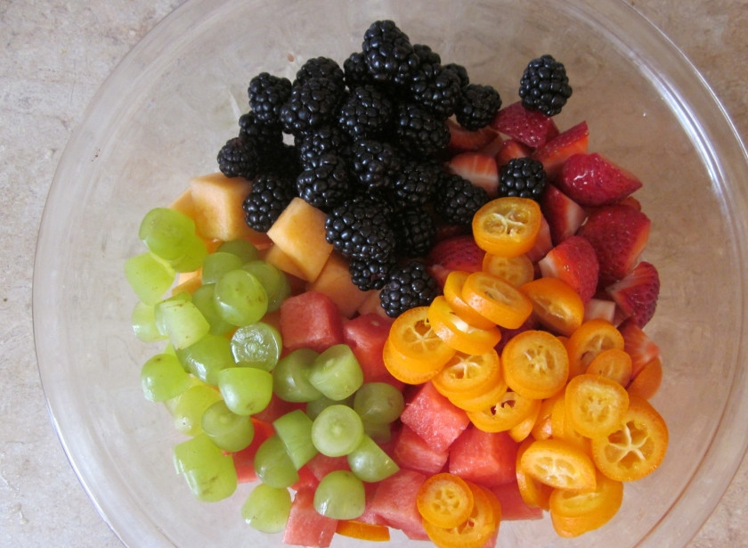 1. Этап. Вкусный фруктовый салат: Следом добавьте все остальные ингредиенты: виноград и ягоды можно оставить целыми (если клубника слишком крупная, тогда порежьте ее), арбуз и дыню порежьте кубиками, кумкват и так небольшой, поэтому просто порежьте его колечками.