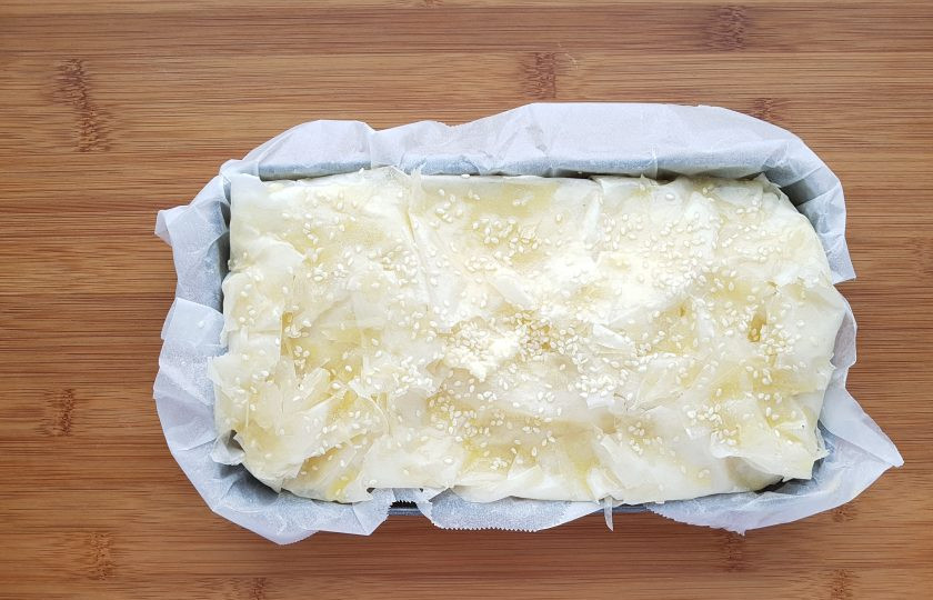 1. Этап. Рыбный пирог с тестом фило: Оставшуюся заливку вылейте сверху. Заверните края теста и укройте пирог. Смажьте растопленным сливочным маслом и посыпьте кунжутом.