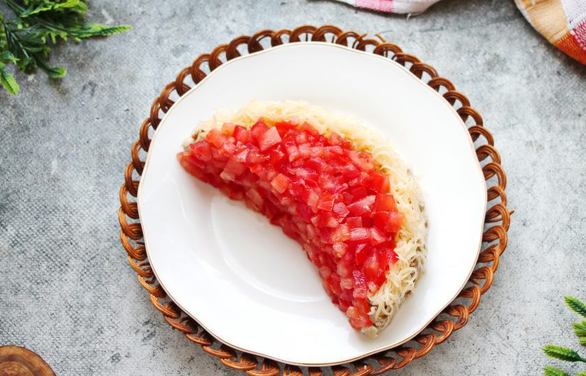 1. Этап. Салат Арбузная долька с курицей и грибами: Помидоры порежьте мелким кубиком и выложите сверху и поверх внутренней части полукруга, прижмите.