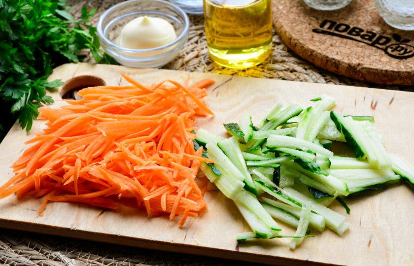 1. Этап. Салат Обалденный с куриным филе: Морковь натрите на терке, а огурцы нарежьте тонкой соломкой.