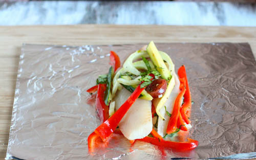 1. Этап. Камбала, запеченная с овощами: Запекать рыбу будем в фольге, сделаем три порции рыбы с овощами. Отрываем три куска фольги, необходимой величины и в центр каждой выкладываем часть овощей, на них - филе камбалы. Затем сверху еще присыпаем овощами. Сбрызгиваем уксусом.